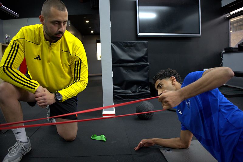 Dion Tsolakis coaching Hassan Ayub through a banded drill